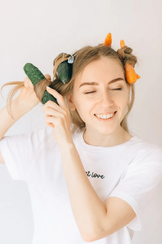 a woman in white shirt with vegetables on her hair