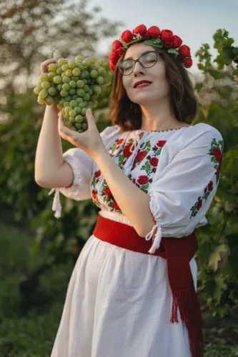 woman in traditional clothing holding grapes