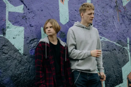 two teenagers in front of a mural