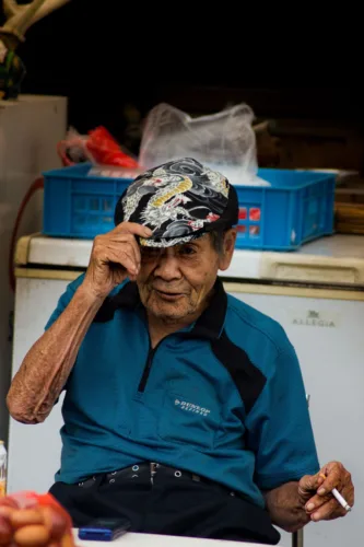 elderly man tipping patterned cap in casual setting