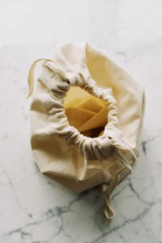 white textile bag with drawstrings placed on marble table
