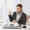man with cold sitting at desk