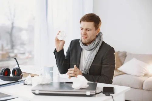 man with cold sitting at desk